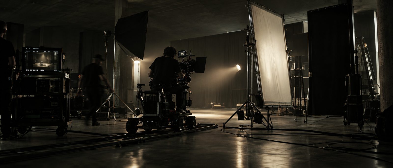 Set de gravação com câmera de cinema num dolly, rebatedor e luz quente